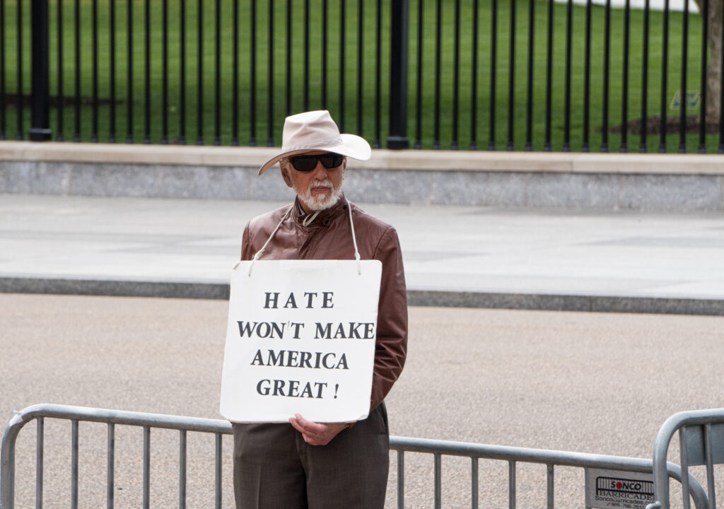 A man stands outside of the White House with a hate won't make america great sign. 