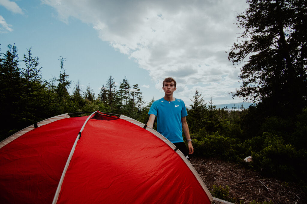 Noah stands infront of his tent as he camps in Acadia National Park. 