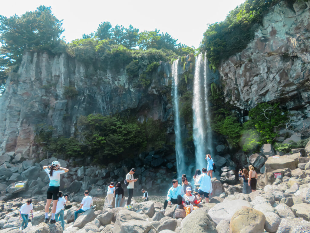 Jeongbang Waterfall full of tourists on Jeju Island.