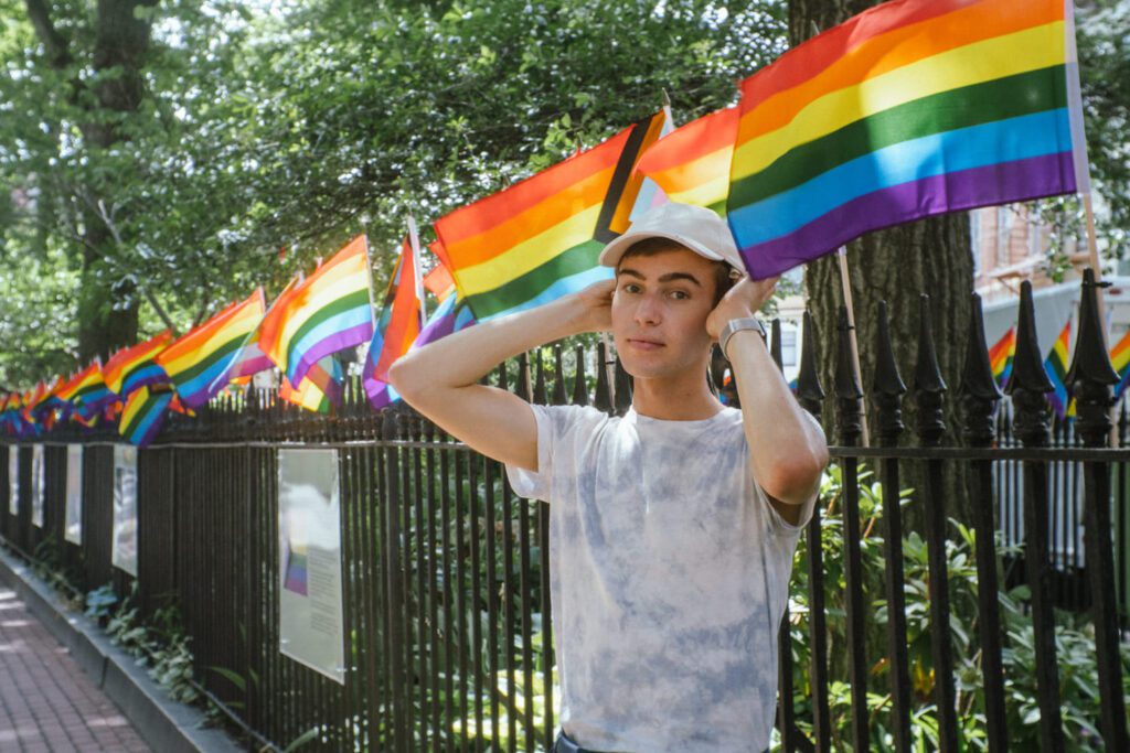 Noah stands infront of Pride Flags at Stonewall National Monument