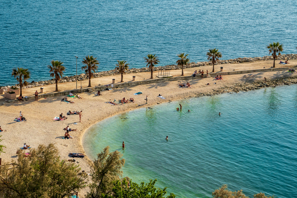 A beach in Split, Croatia full of people swimming and sunbathing. 