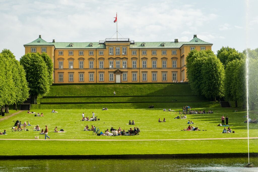 People picnic and sunbathe at Frederiksberg Slot in Copenhagen. Visiting here is great during your solo trip to Copenhagen.